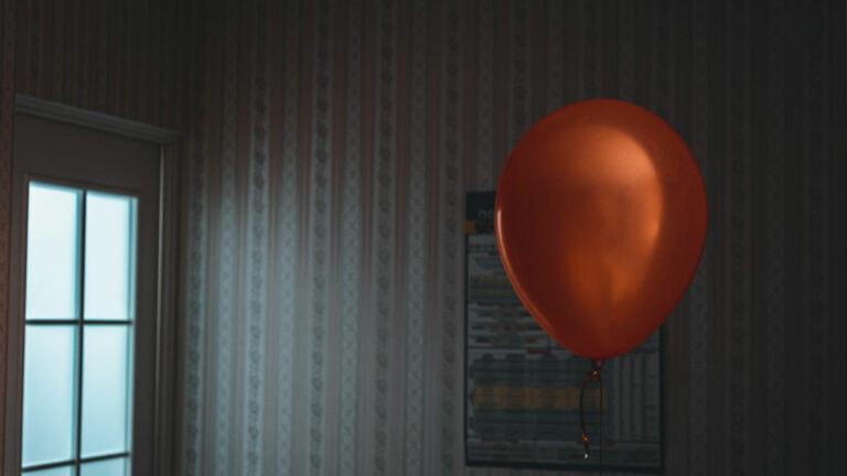 Червен балон, реещ се в стая